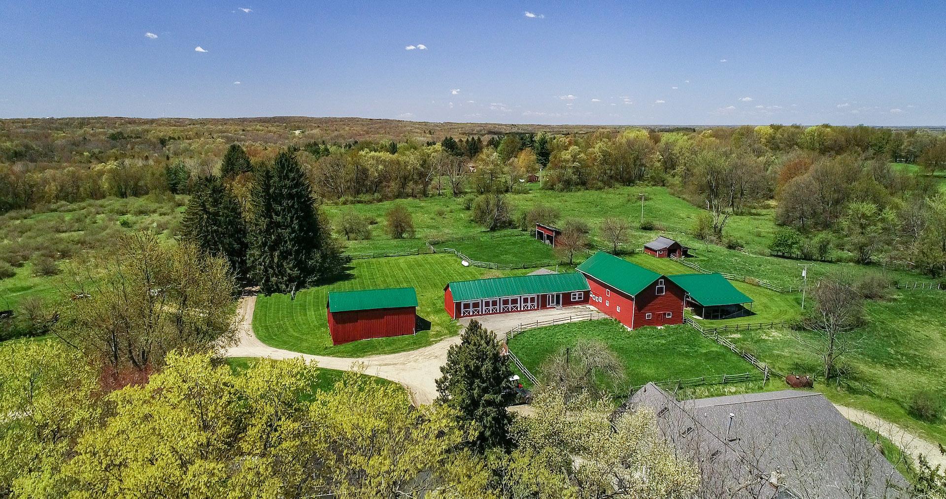 Aerial view of red barns and wooded acreage in Lapeer County