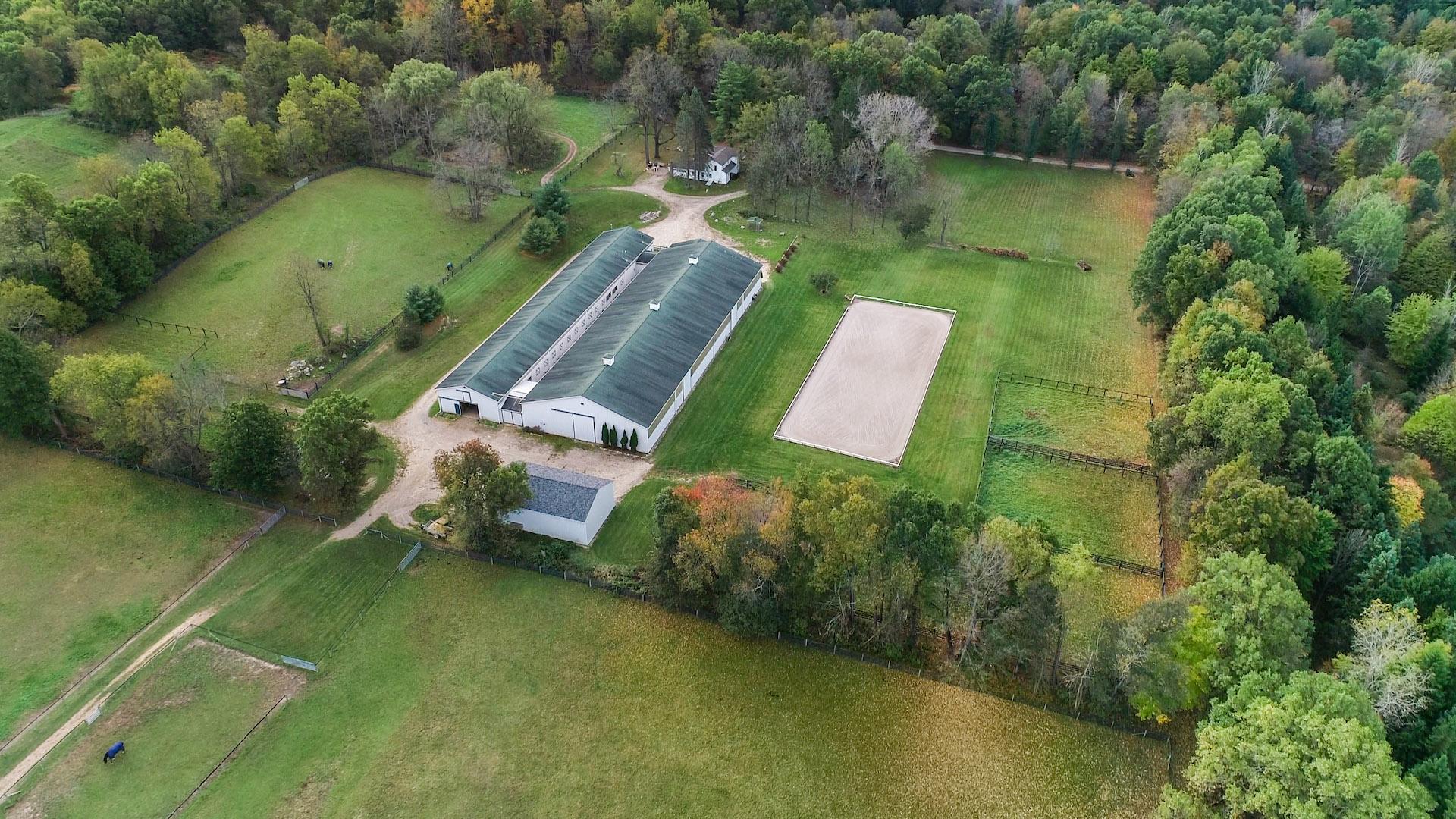 Aerial view of an indoor arena, barns and outdoor arena in Davisburg
