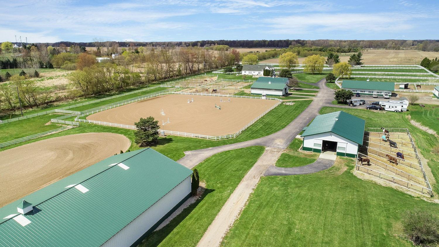 Aerial view of an indoor arena, outdoor arenas and barn in Williamston