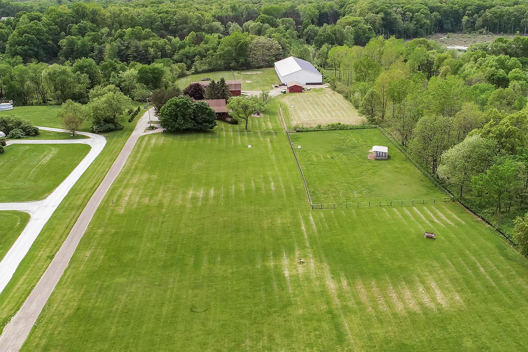 Aerial view of a horse barn, arena and fenced pastures in Howell
