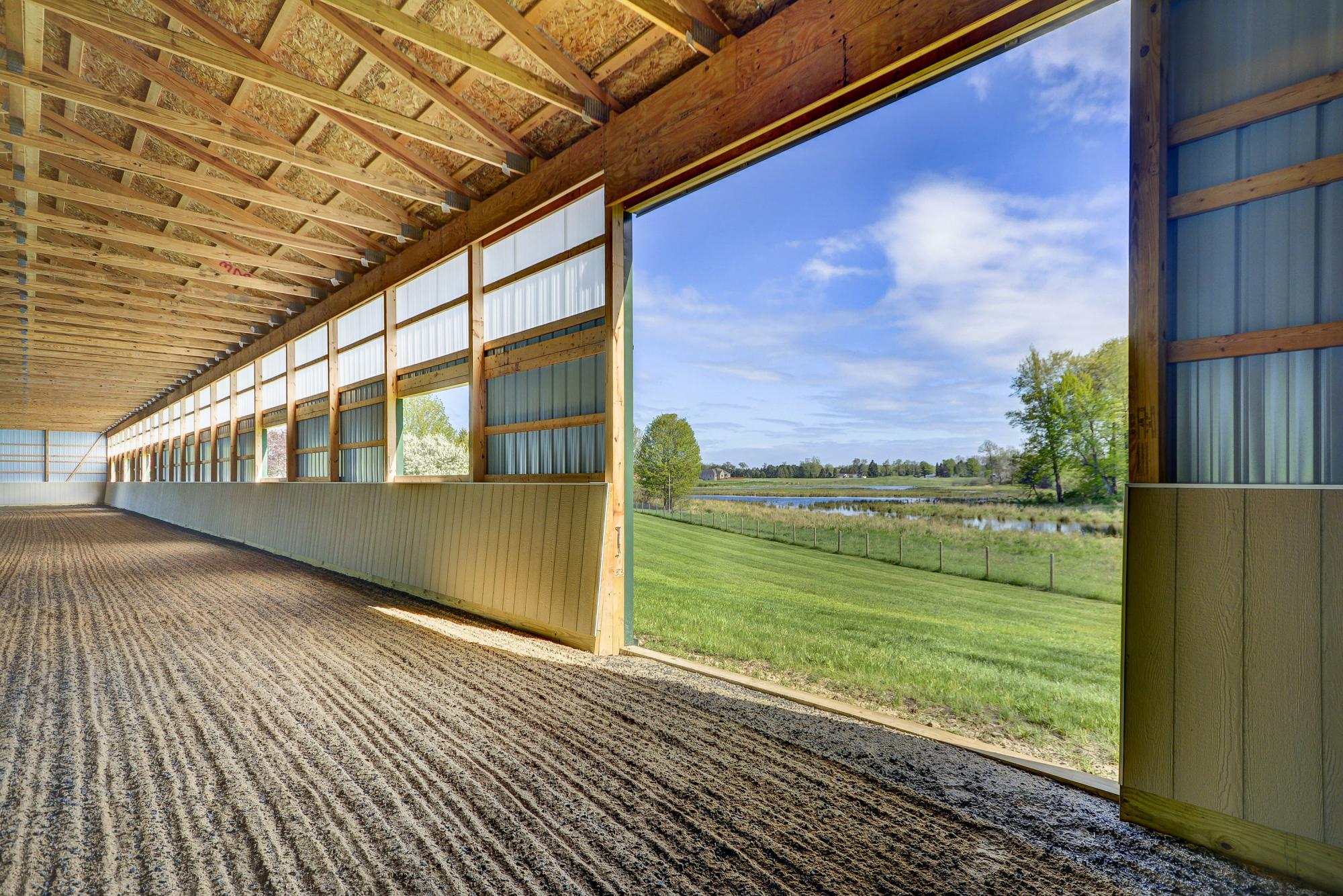 Indoor riding arena opening onto pasture at a Michigan equestrian property