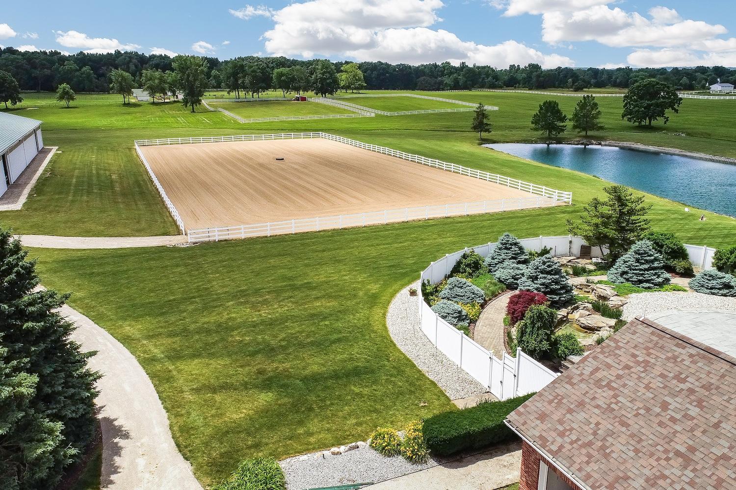 Aerial view of an outdoor arena, pond and home in Washtenaw County