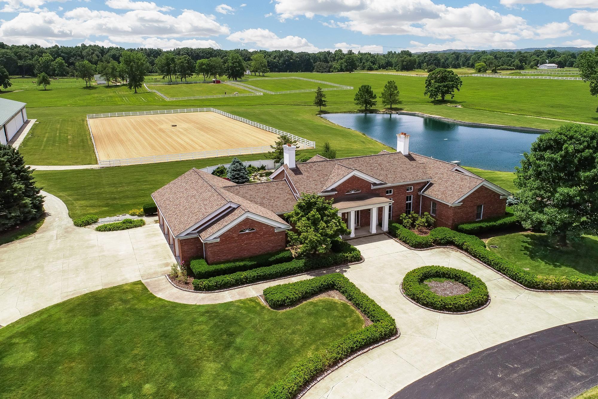 Aerial view of the 62-acre Scio Church Rd equestrian estate in Chelsea with brick home, outdoor arena and pond